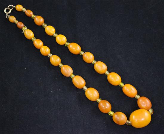 A single strand graduated oval amber necklace with yellow paste spacers, 15.5in.